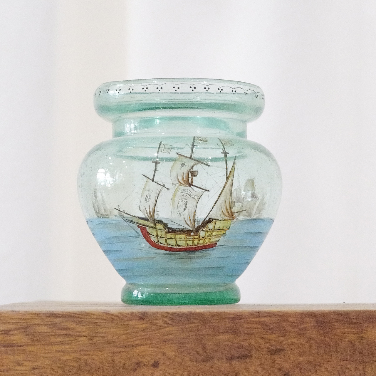 Blown glass vase with a painted scene depicting sail boats on the water.