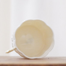This vintage Belleek mug has a scalloped rim and design featuring yellow flowers and a branch as a handle.
