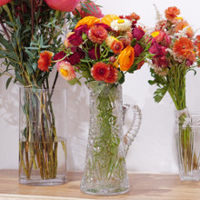 Flower bouquet of a mix of ranunculus, strawflower, spray roses, and astilbe in sunset colors.