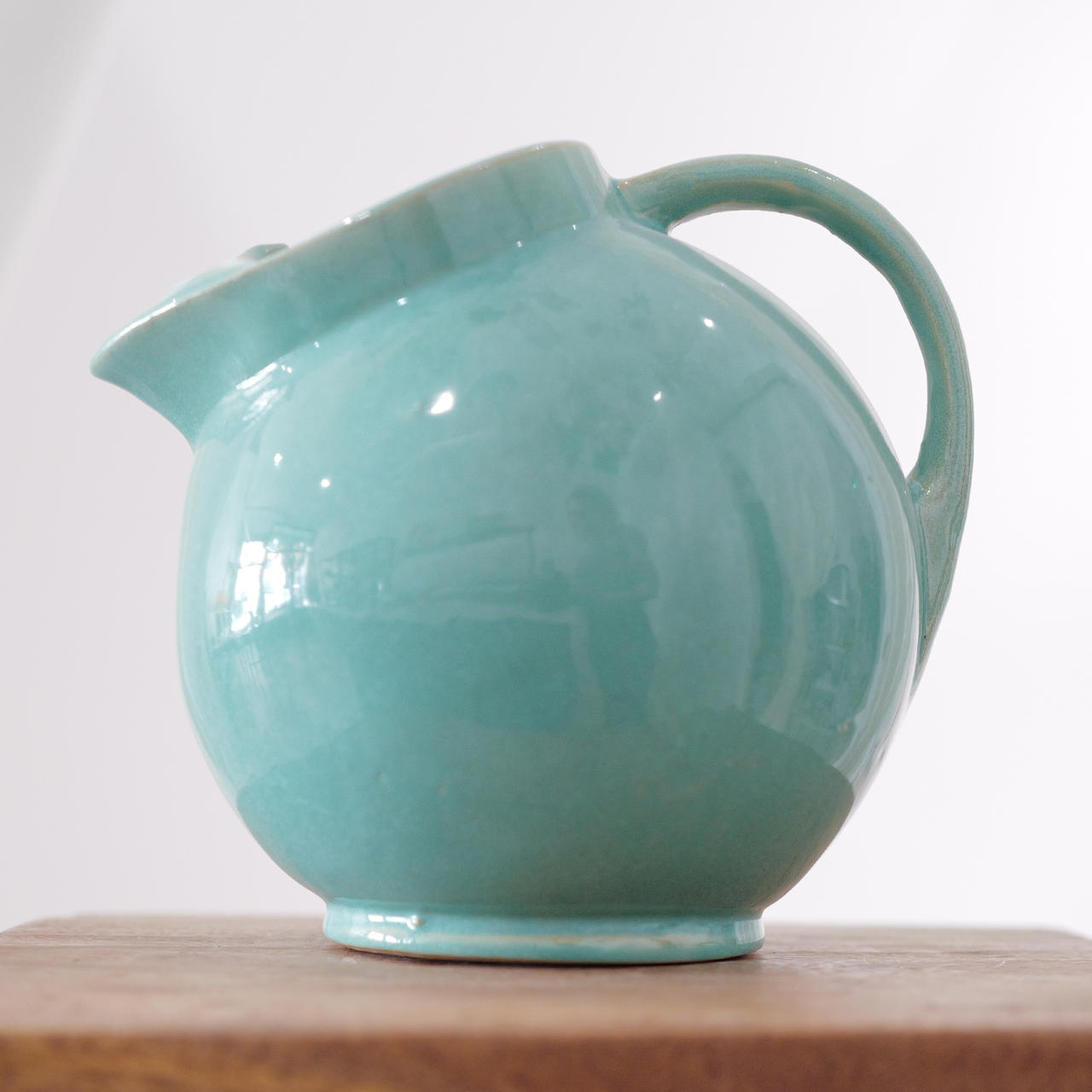 Rounded turquoise ceramic pitcher with smooth glossy glaze and sculpted spout.