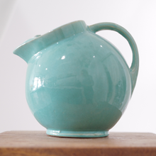 Rounded turquoise ceramic pitcher with smooth glossy glaze and sculpted spout.