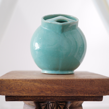 Handmade turquoise pitcher featuring a spherical body and raised foot ring.