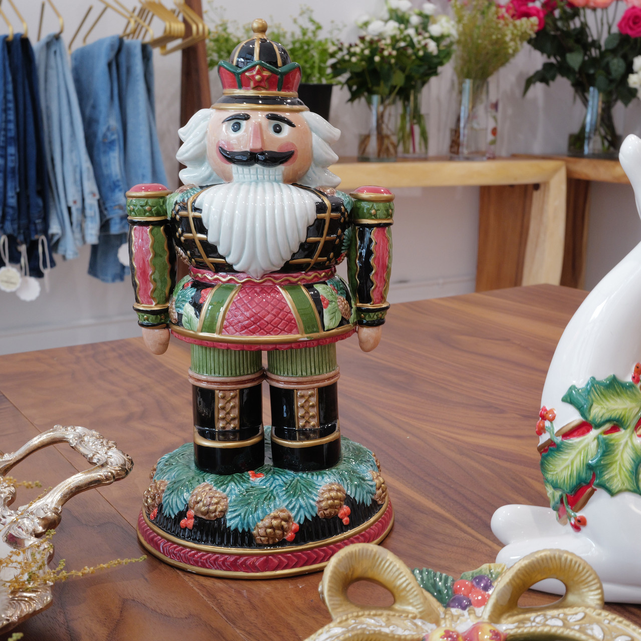 Vintage Fitz and Floyd Signature Collection nutcracker figurine on pinecones and evergreens. Hand-painted ceramic holiday decor with gold accents and sculptural detail.