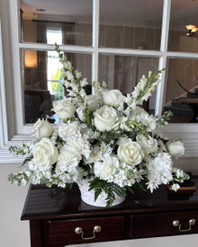 Elegant white sympathy flowers arranged in a classic white basket.