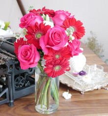 This bright, bold, and beautiful red and pink bouquet has small pops of white.  Featuring gerbera daisies and pink roses.