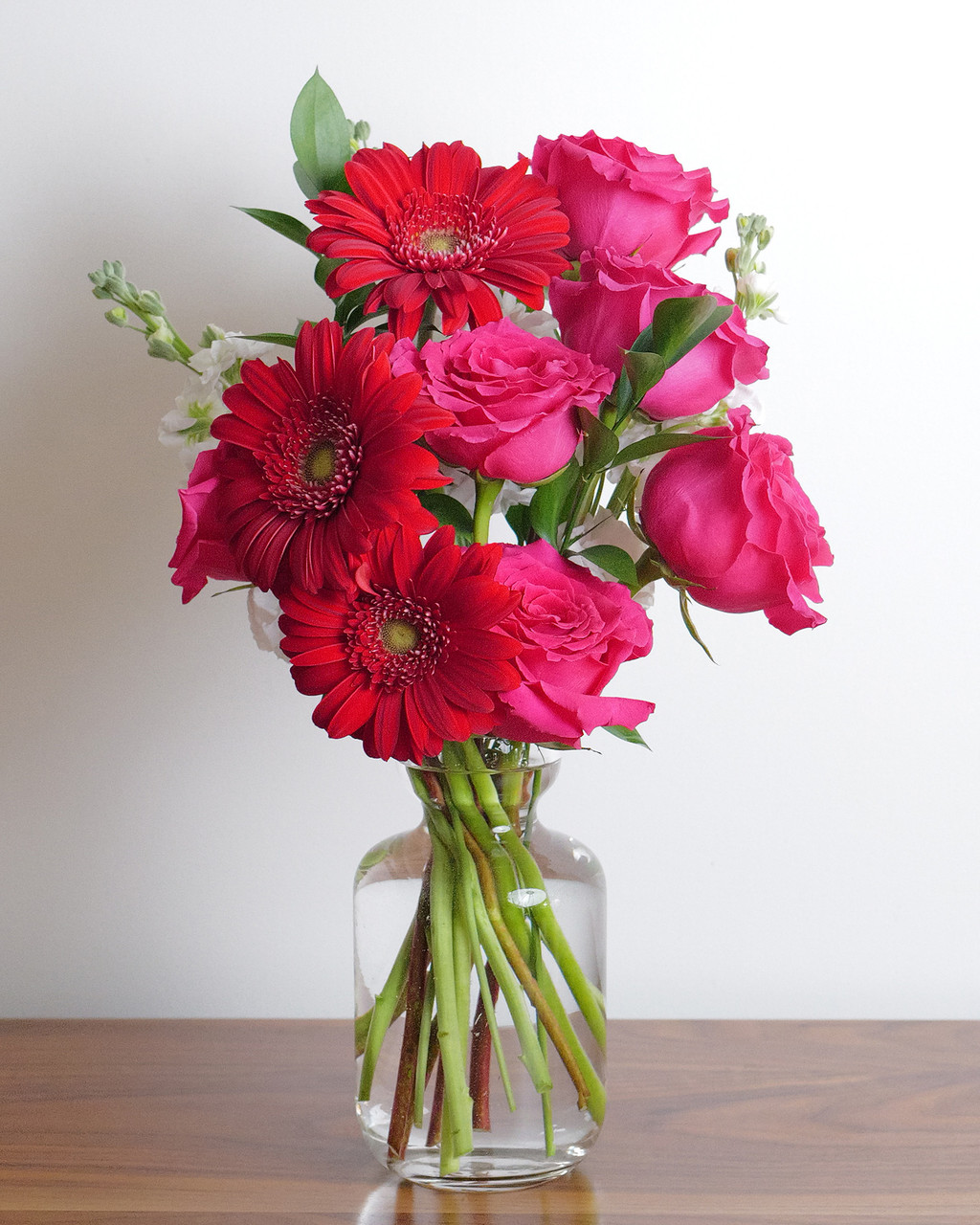 This bright, bold, and beautiful red and pink bouquet has small pops of white.  Featuring gerbera daisies and hot pink roses.