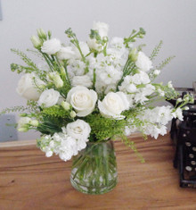 White rose and snapdragon sympathy arrangement with airy greenery in a clear glass vase.