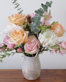 Peach, blush and white flower arrangement in a handmade ceramic vase with gold rainbow detail.