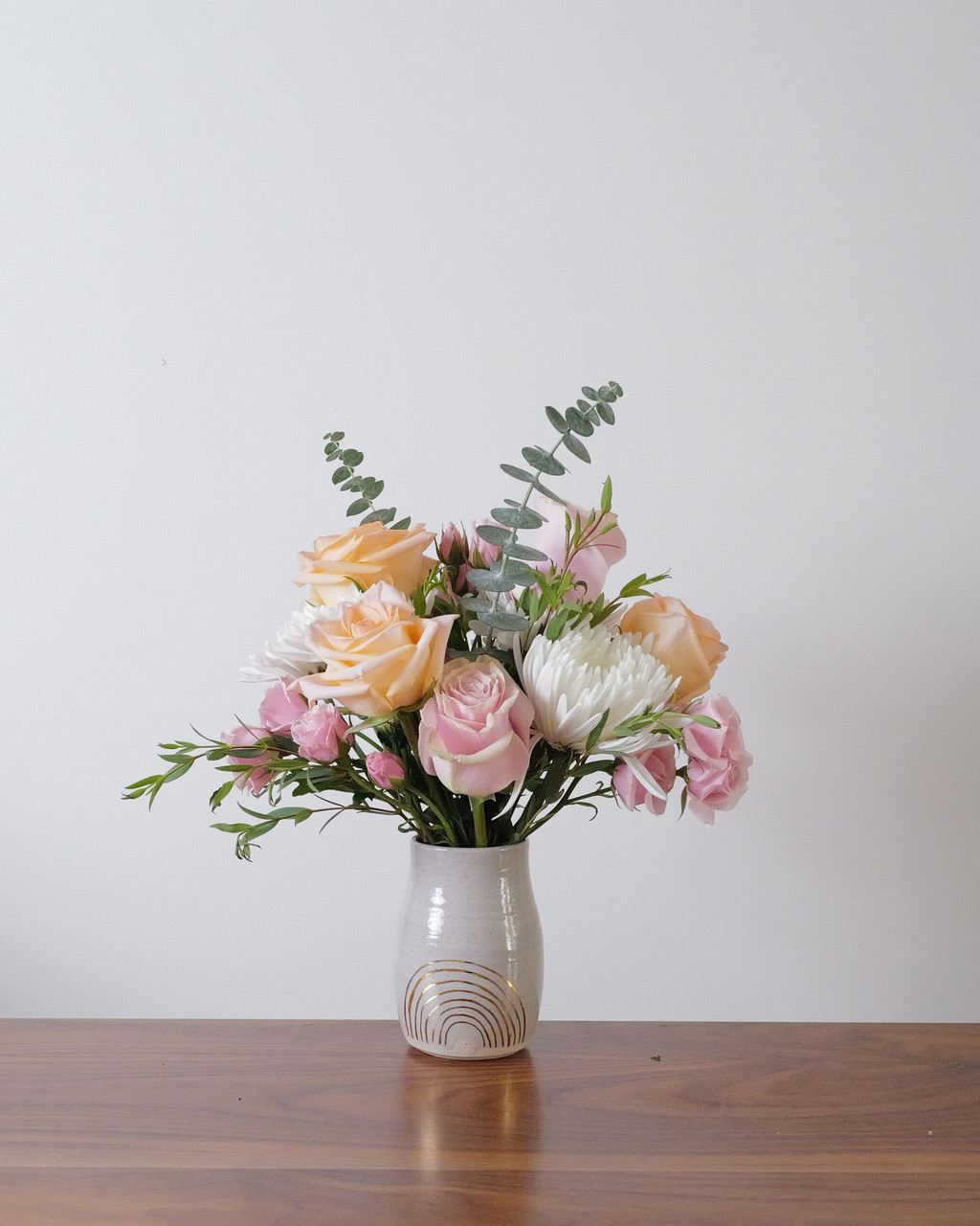 Lucky Gal features peach, blush and white flowers in a handmade Pickle Pottery ceramic vase with a gold rainbow design. Chicago flower delivery.
