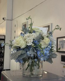 Lake Effect arrangement in a clear glass vase on a wood table, Lake Michigan blues and cloud-white flowers
