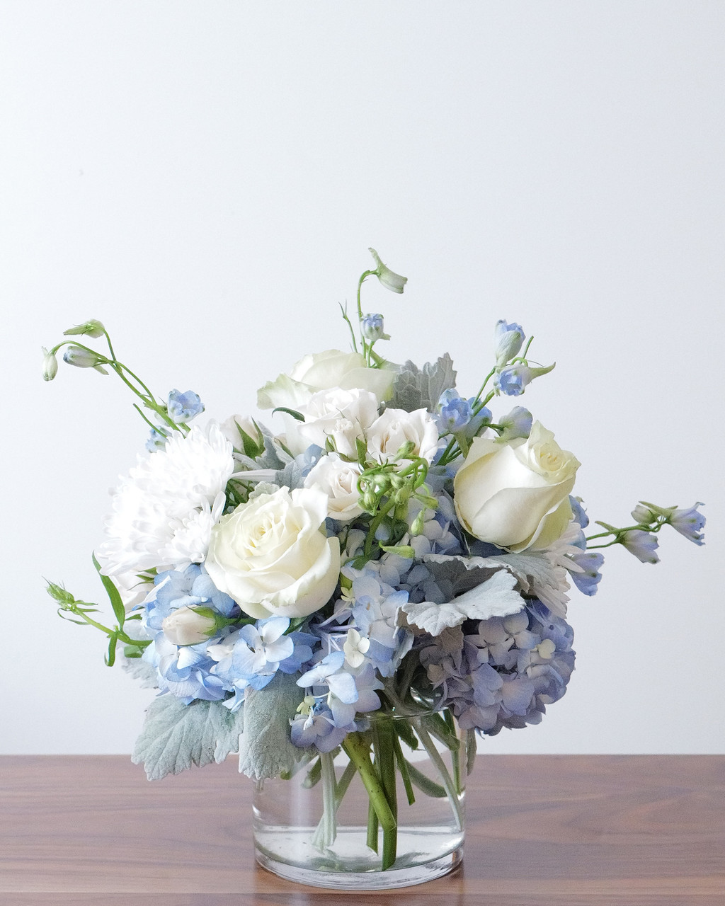 Lake Effect: blue hydrangea, white roses, and delphinium in a clear glass vase. Hand-designed in Chicago by Flowers by Figgi.