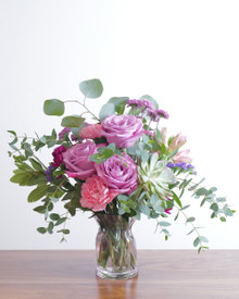 Close-up of the living echeveria succulent nestled among pink roses and purple statice in The Keeper arrangement, showing the rosette that can be replanted after the flowers fade.