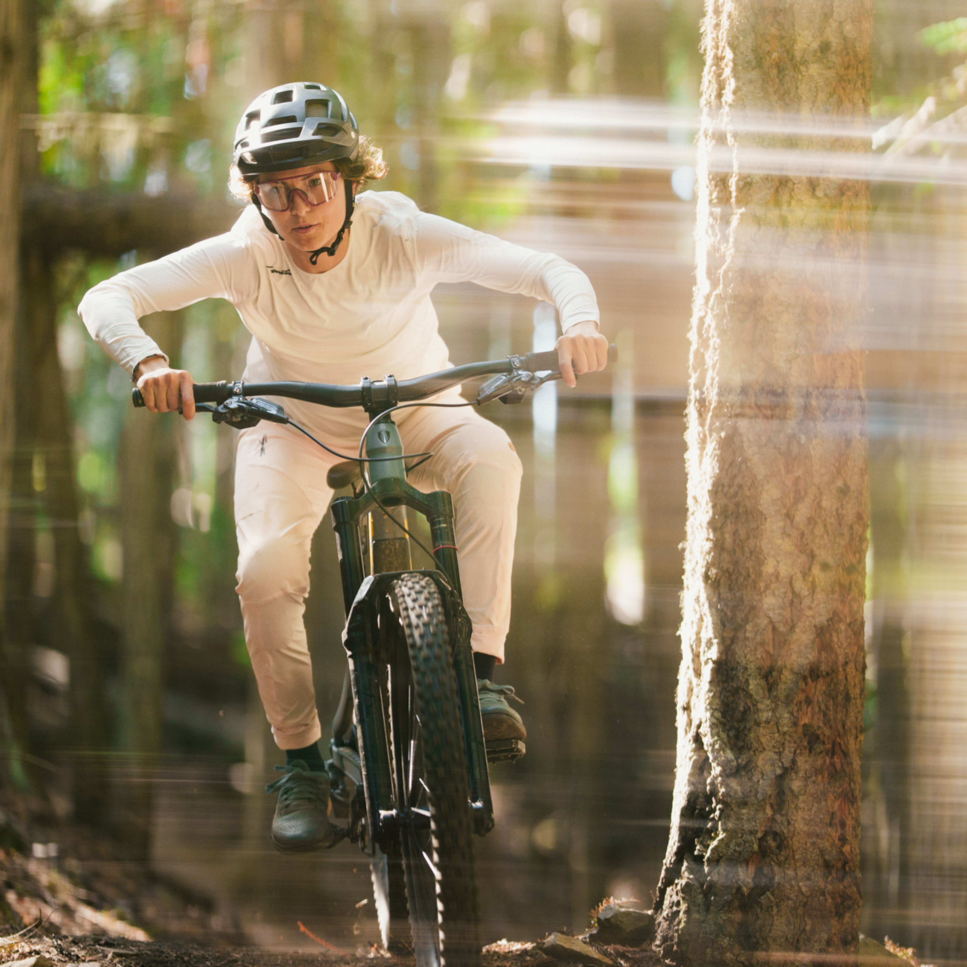 female mountain biker descending wearing a coconut colored jersey