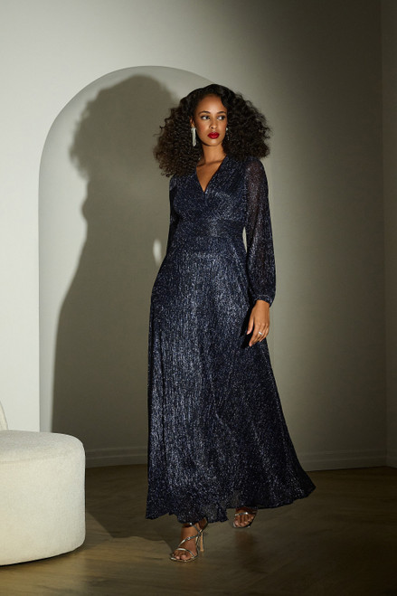 Joseph Ribkoff Lurex Plissé Mesh Wrap-Front Gown (253780). This full-length gown radiates class and sophistication, featuring a wrap-style V-neckline, a wide spliced waistband, and long puffed sleeves for a timeless, elegant look. Crafted from shimmering plissé fabric, it cascades gracefully to the floor, creating a sweeping, unforgettable silhouette. The A-line design ensures a flattering fit, enhancing your figure with effortless beauty. Part of the Signature Collection.