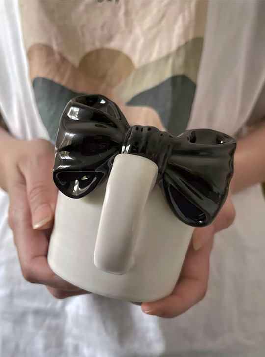 The unique bow tie design of the "Papillon" mug by TUTU adds a playful touch to any drink.