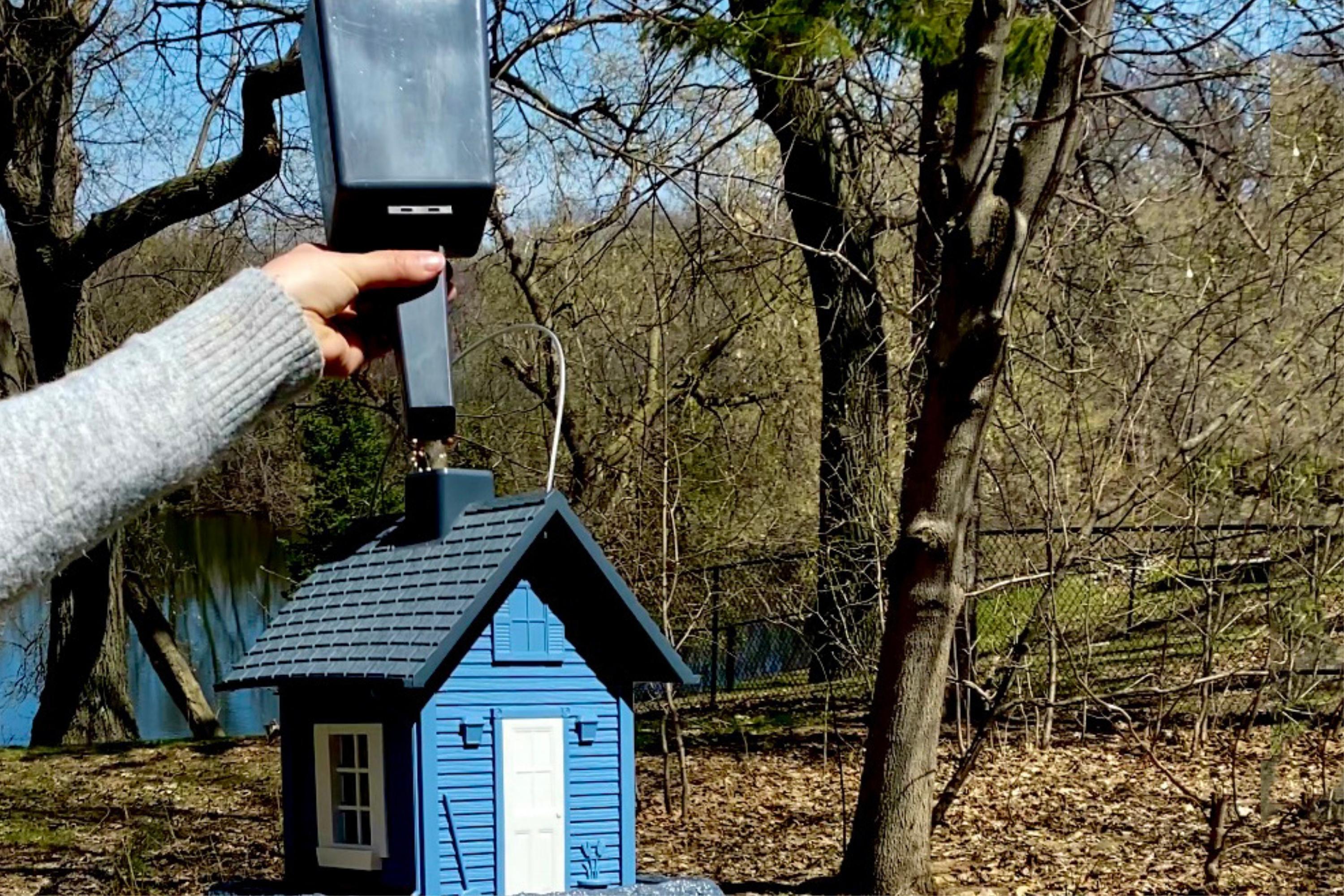 Feeder Filler Scoop funneling bird seed into a Blue Cottage Birdfeeder