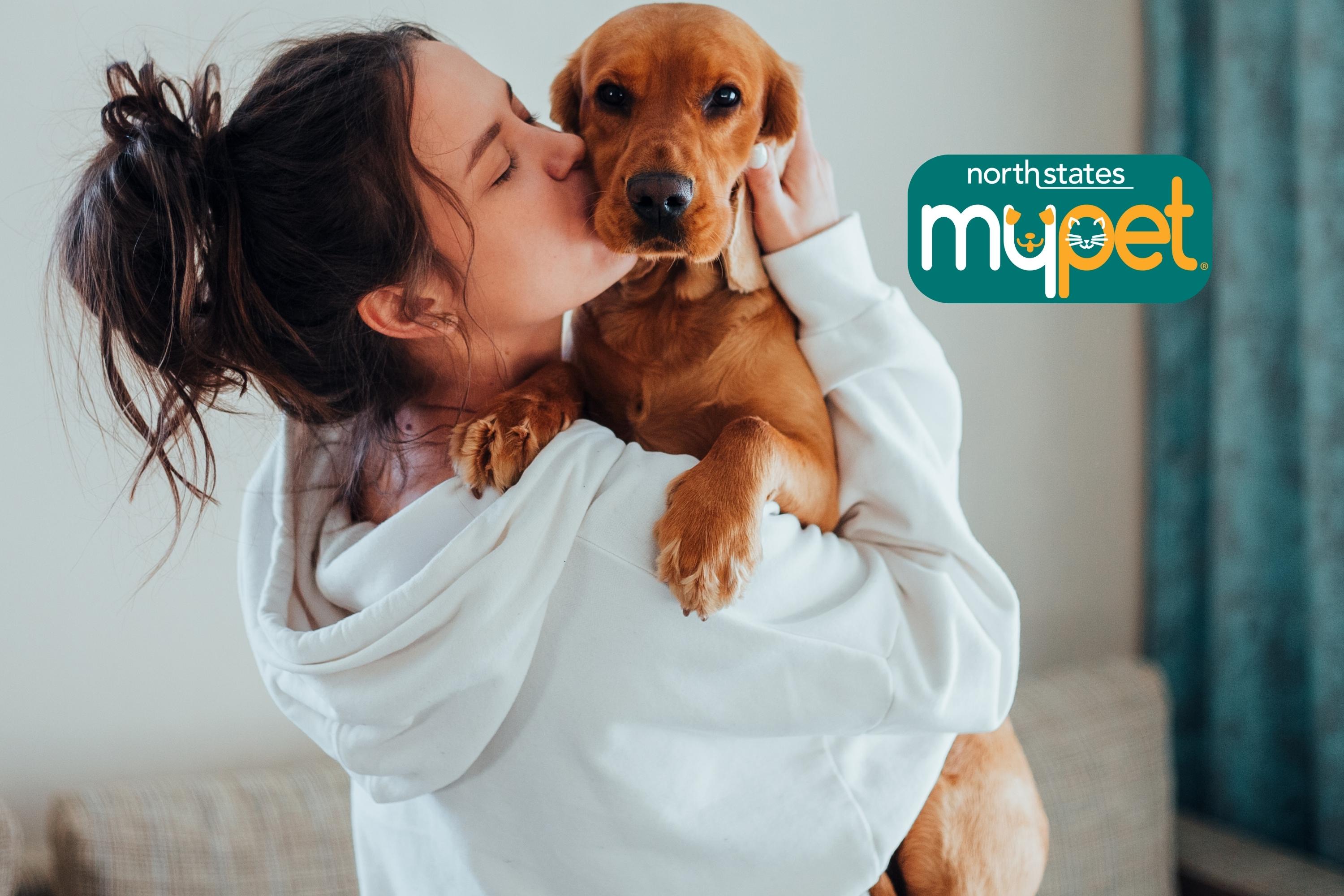 woman holding a brown dog while kissing its cheek