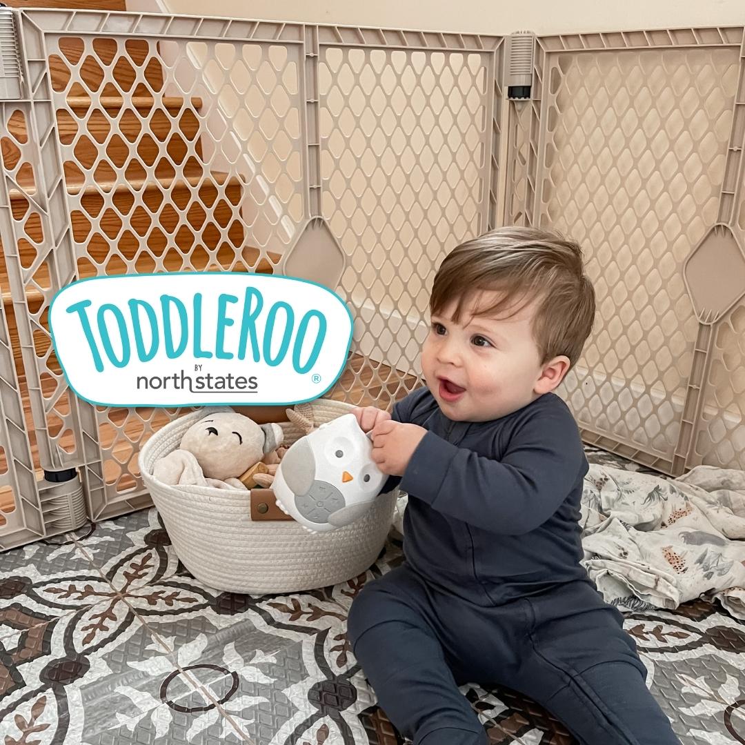 Smiling baby sitting on a Mosaic Play Mat and inside a Superyard Sand