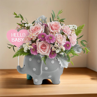 Pink and white floral arrangement featuring roses and chrysanthemums displayed in a gray polka-dot elephant keepsake vase with a â€˜Hello Babyâ€™ sign, perfect for welcoming a newborn or baby shower gift. Standard Size