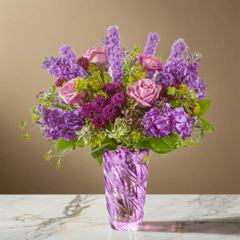Purple garden style flower arrangement with rose, stock, liatris, scabiosa, and fresh greenery arranged in a purple art glass vase