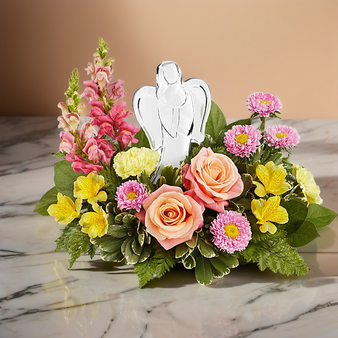 Angels Embrace Bouquet featuring roses, snapdragons, carnations and alstroemeria arranged with greenery around a keepsake angel figurine centerpiece.