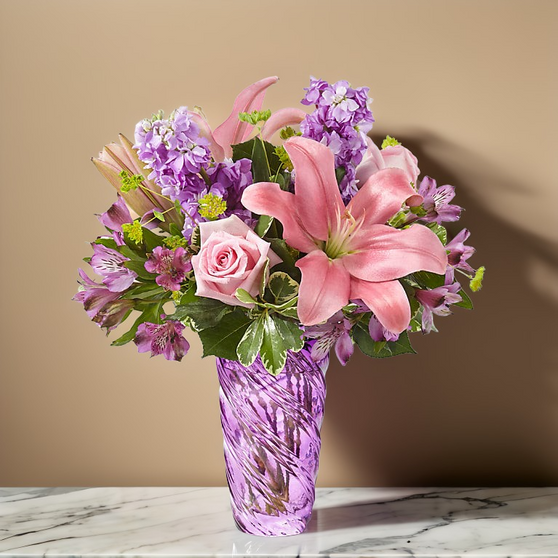 Spring mix of pink and lavender flowers in a lavender swirl vase