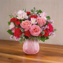 Mixed pink and red bouquet in a pink container sitting on a table
