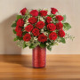 Deluxe Love Spark Bouquet featuring classic roses arranged with fresh greenery in a red glass vase