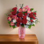Gorgeous Premium Gem Bouquet featuring red roses, carnations, alstroemeria, and white accent flowers arranged in a pink glass vase