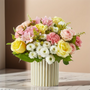Pastel pink rose bouquet with yellow roses, white cushion mums and alstroemeria in a modern fluted ceramic vase on marble table