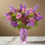 Purple garden style flower arrangement with rose, stock, liatris, scabiosa, and fresh greenery arranged in a purple art glass vase
