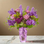 Purple garden style flower arrangement with rose, stock, liatris, scabiosa, and fresh greenery arranged in a purple art glass vase