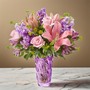 Deluxe Spring mix of pink and lavender flowers in a lavender swirl vase