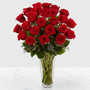 Red roses arranged in a clear glass vase sitting on a white table