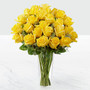 Yellow roses arranged in a clear glass vase sitting on a white table