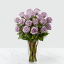 Lavender roses arranged in a clear glass vase sitting on a white table