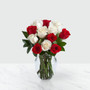 6 red and white roses arranged in a vase with greens on a marble table