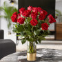 A gorgeous 18 red rose bouquet sitting on black marble table in a living room