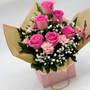 Pink roses and carnations designed in a pink purse container image from side angle
