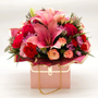 Pink Luxe Bloom Purse featuring pink lilies, roses, carnations, and accent blooms arranged in an elegant blush handbag box with gold chain detail