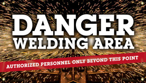 Picture of Workplace Safety Banner that features a dark background lit up by sparks, as something is being welded in the background. In front of this in large bold white letters the banner reads "Danger welding area". Below this there is a red stripe with smaller white text that reads "Authorized personnel only beyond this point". 