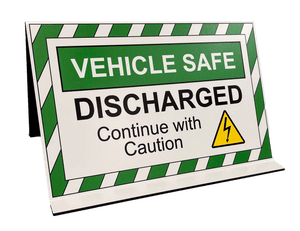 Image of the green and white high visibility sign features the text: "VEHICLE SAFE DISCHARGED - CONTINUE WITH CAUTION", with a yellow electrical discharge symbol, at a 45 degree angle.