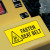 A photograph of a yellow 12205 forklift label, reading fasten seat belt with graphic installed on machinery.