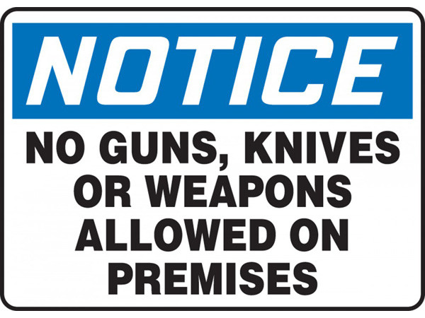 A photograph of a blue and white 01664 notice no guns, knives or weapons allowed on premises OSHA sign.