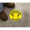 A photograph of the yellow "EAR PROTECTION REQUIRED"  Slip-Gard™ Floor Sign on the floor with a person's boots standing near.