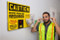 A photograph in of an employee in front of sign installed at facility.