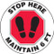 A photograph of a black and white 11228 social distance floor sign, reading stop here maintain 6 ft, with red stop sign and footprints icons.