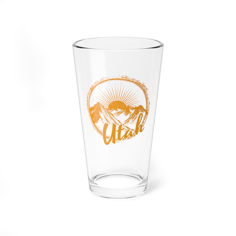 Mountains of Utah Orange Pint Glass, 16oz. Circle orange silhouette design with sun rays and mountains on a classic 16 ounce clear pint glass.