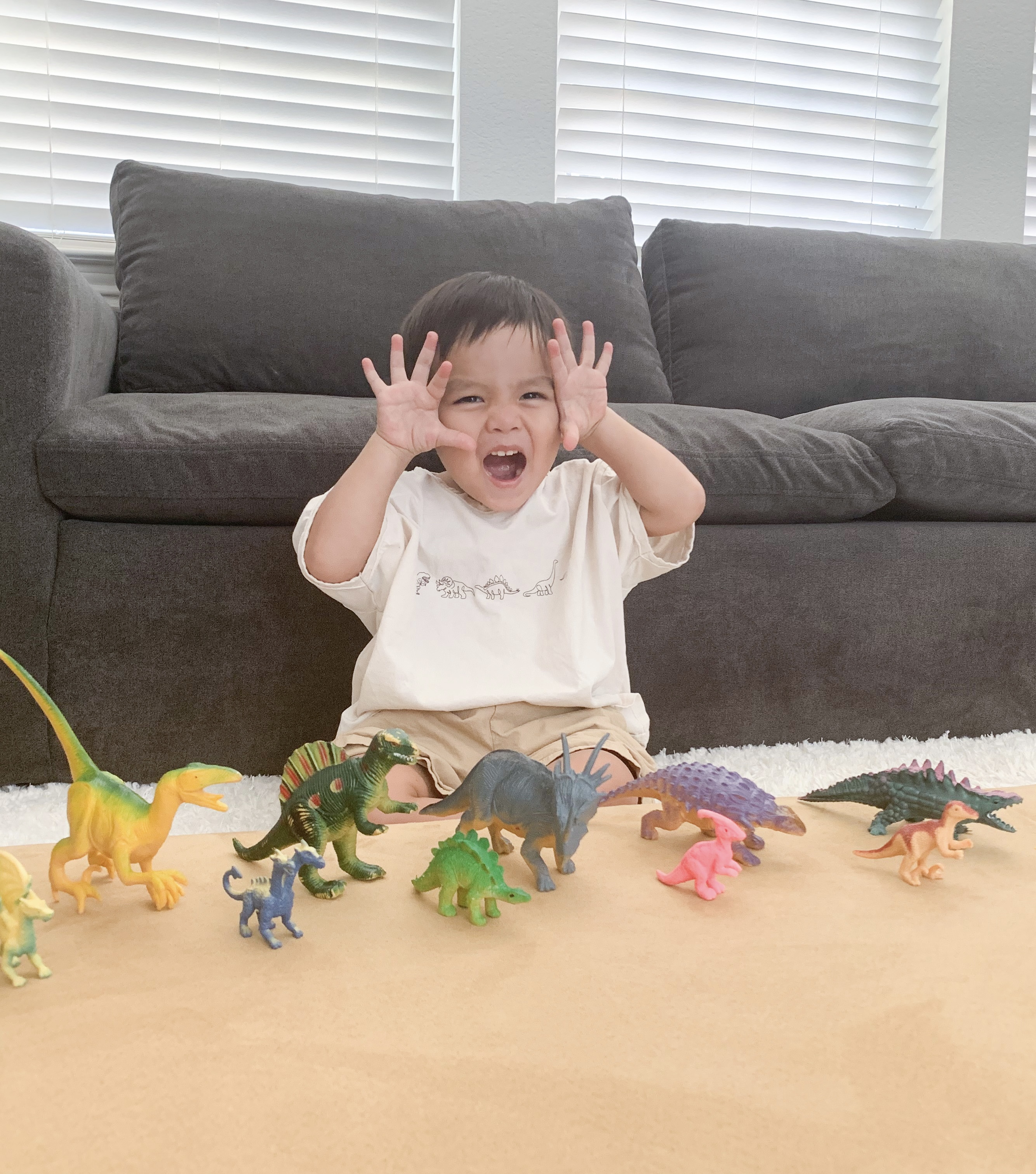 A toddler playing with dino toys and making a face while 