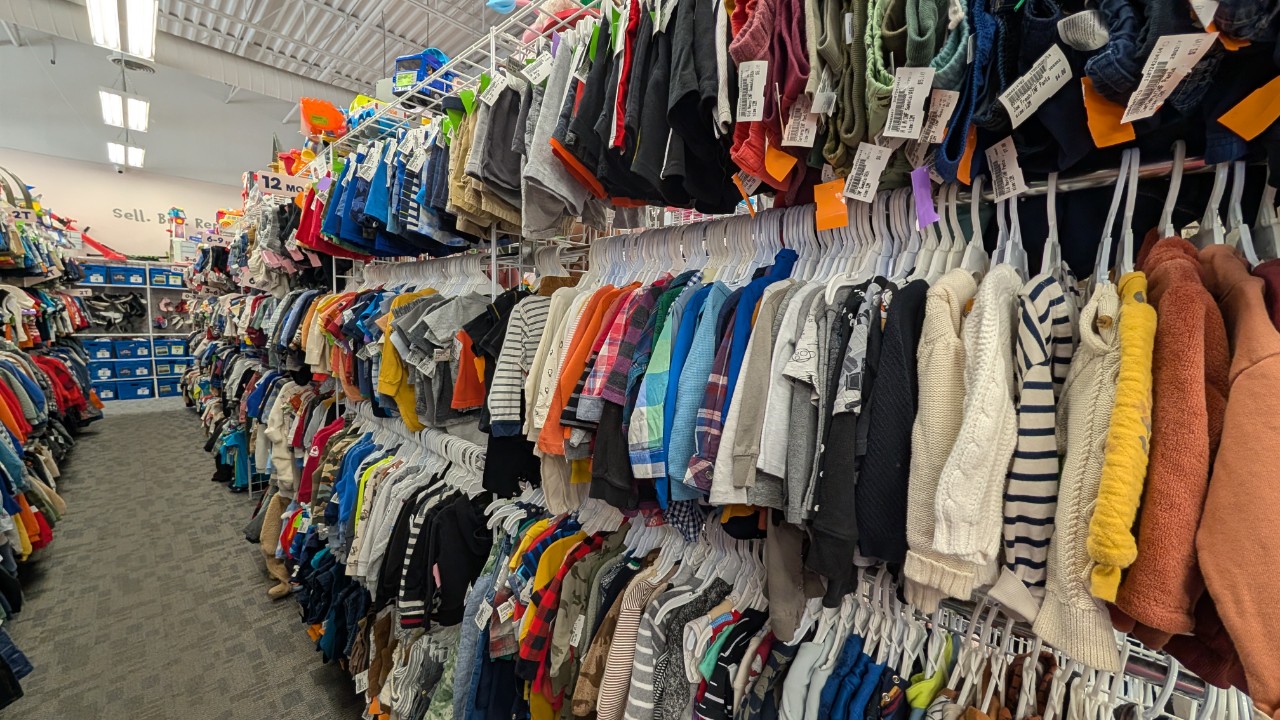 An image of inside the store showing clothes in the aisle, text over image saying 